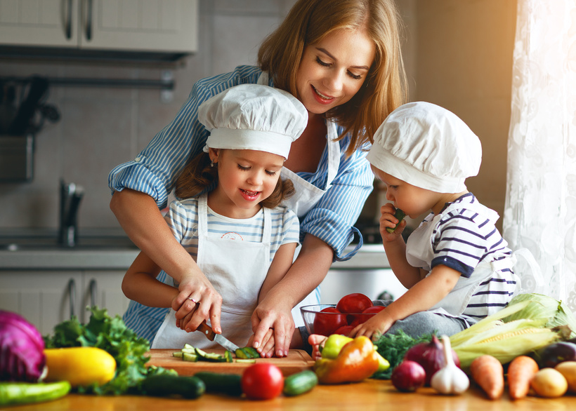 Healthy eating. Happy family mother and children prepares vegetable salad in kitchen